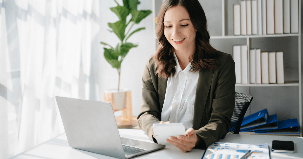 Woman doing accounting on a laptop with calculator and bar-chart reports