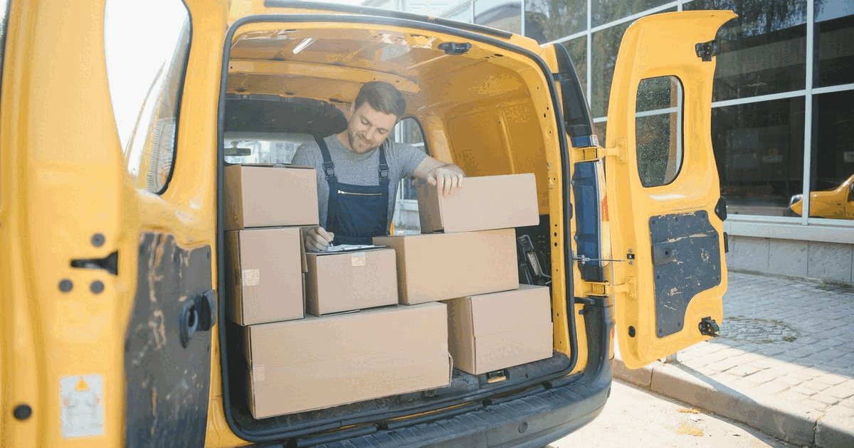 Courier checking boxes on a clipboard in the back of a delivery van