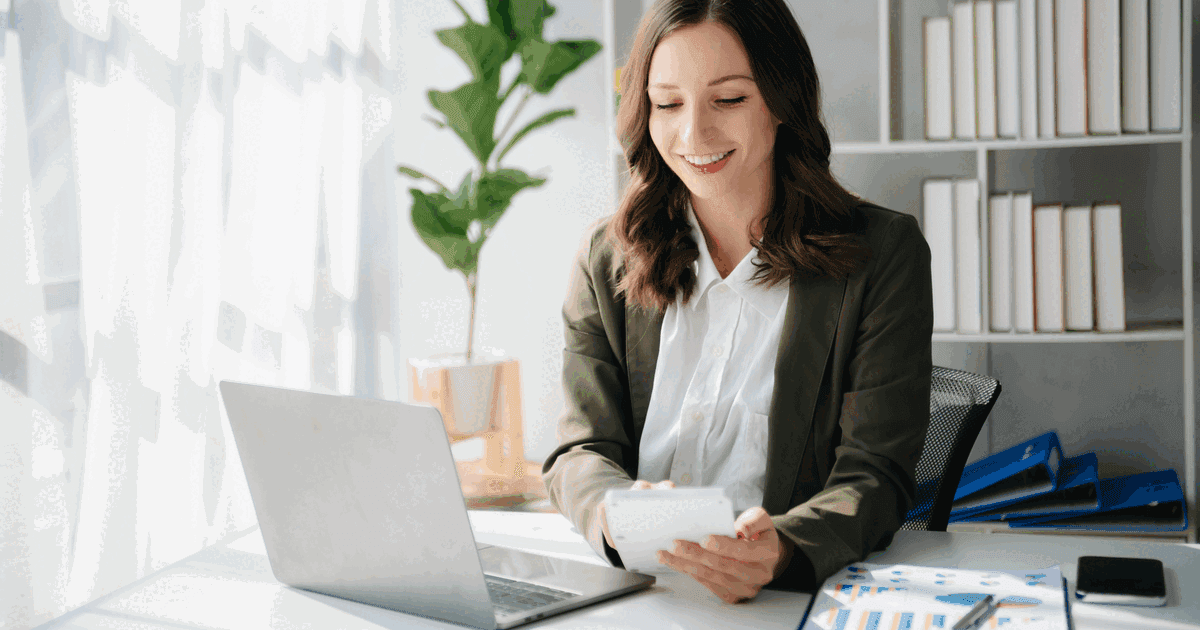 Woman doing accounting on a laptop with calculator and bar-chart reports